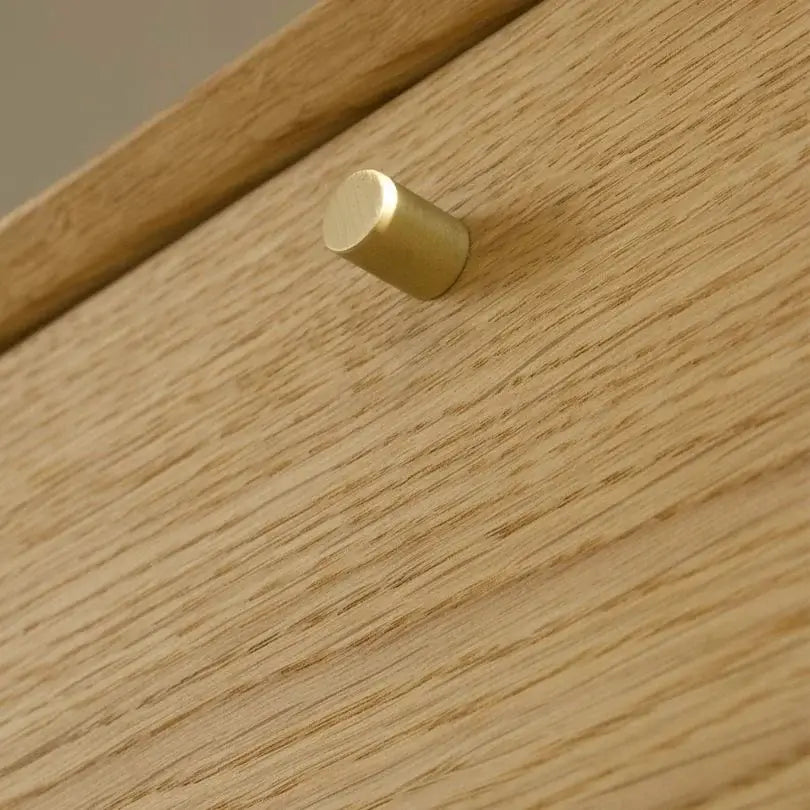 Detalje af guldfarvet knap på egetræsskab med naturlig overflade. Dansk design, produceret i Europa.